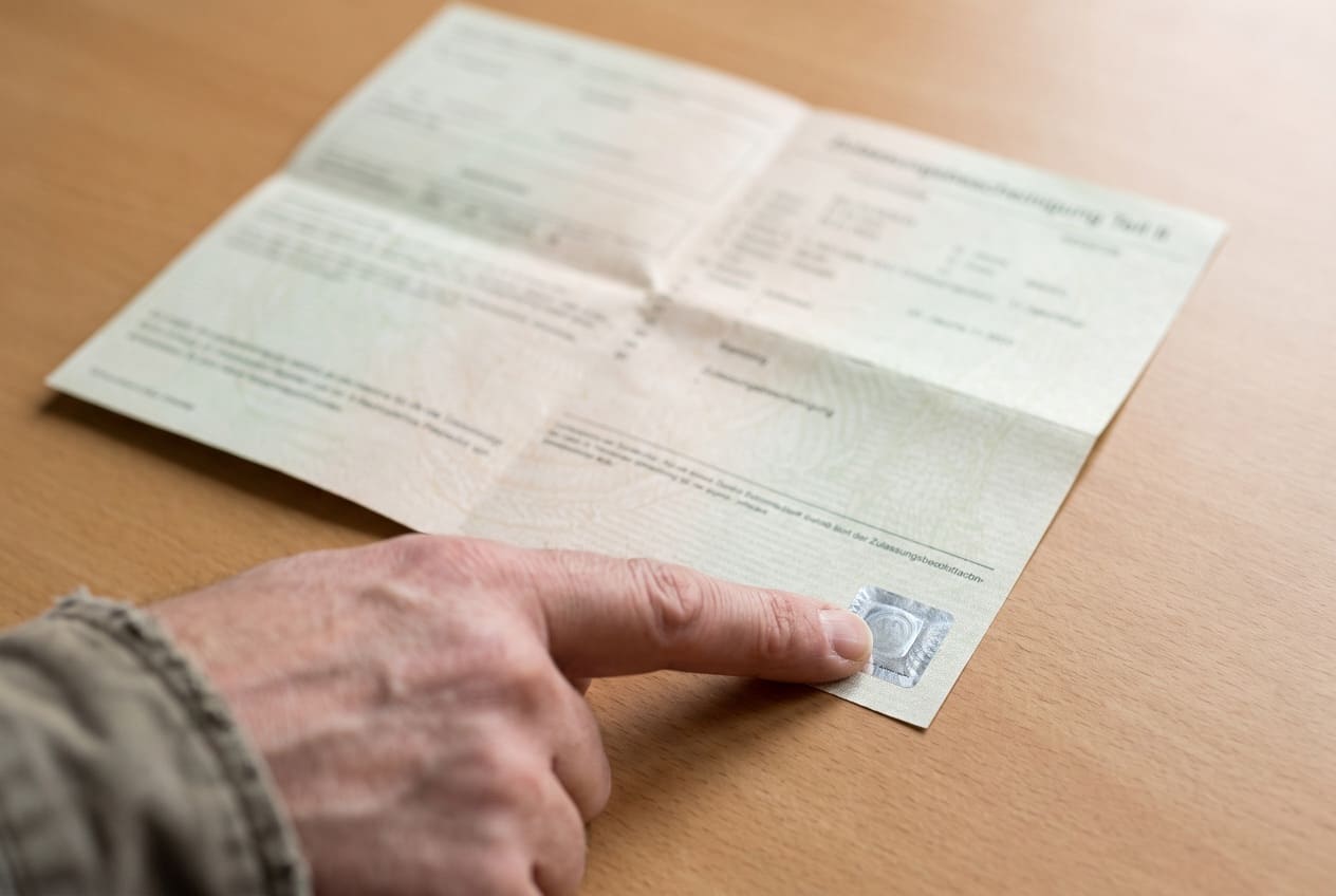 Finger zeigt auf das verdeckte Sicherheitsfeld der Zulassungsbescheinigung Teil II
