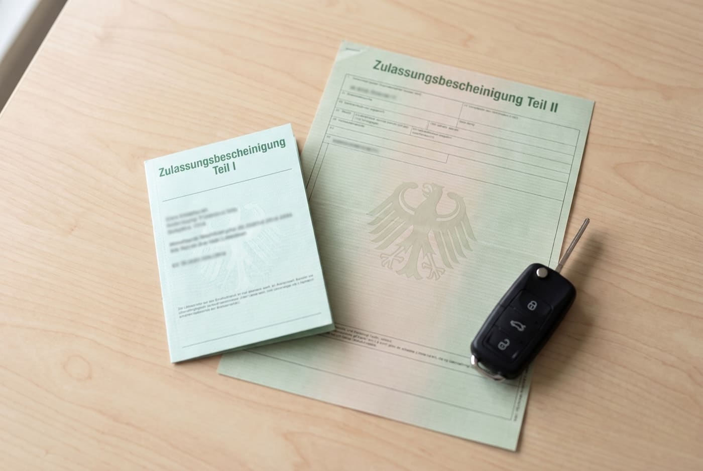 Zulassungsbescheinigung Teil I (Fahrzeugschein) und Teil II (Fahrzeugbrief) nebeneinander auf einem Tisch